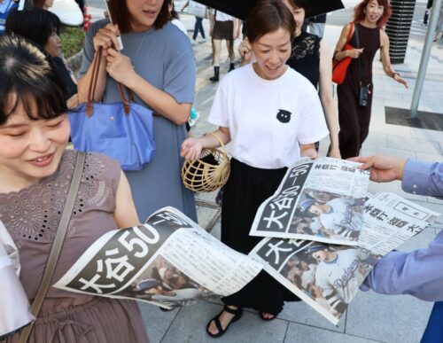  大谷翔平の「50―50」達成を報じる号外を手に取る人たち=2024年9月20日、東京・有楽町（朝日新聞社提供）